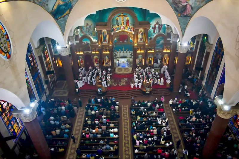 Coptic Orthodox cathedral interior during live worship service — professional audio system installation transforming a highly reverberant domed sanctuary into a clear intelligible worship environment